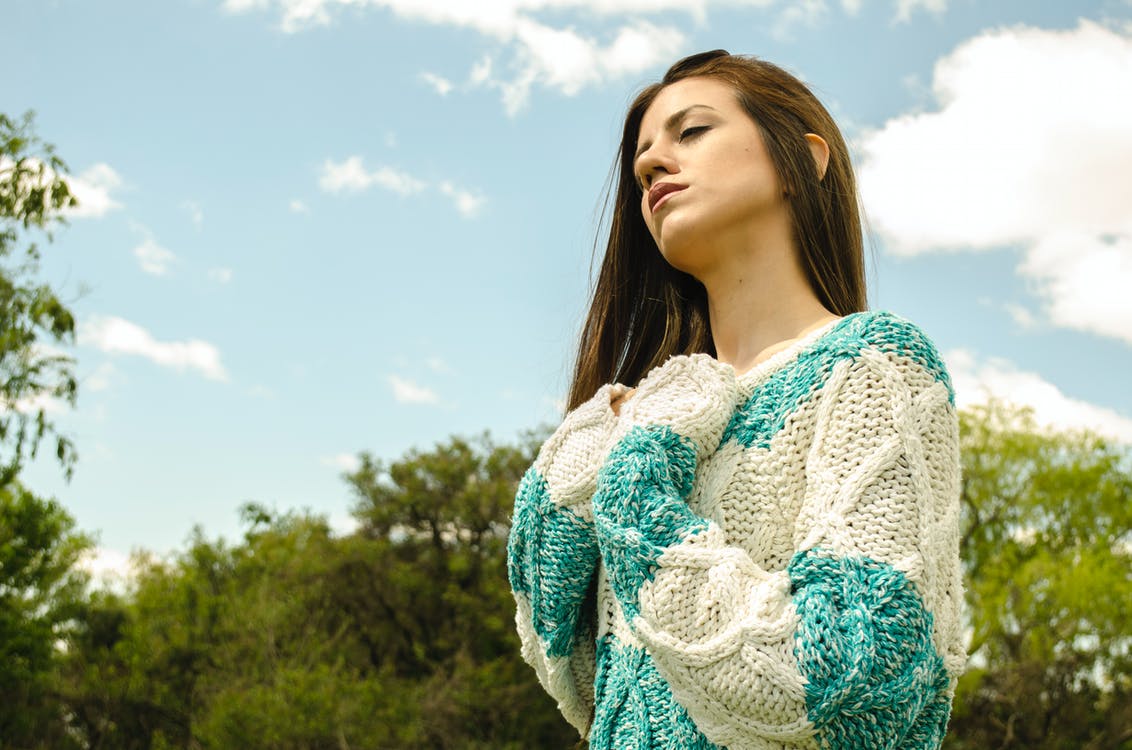 A woman wearing a white and teal crochet sweater