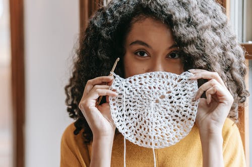 A woman covering her mouth with crochet piece