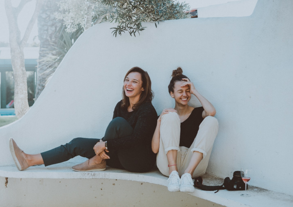 Two women sitting next to each other, laughing. 