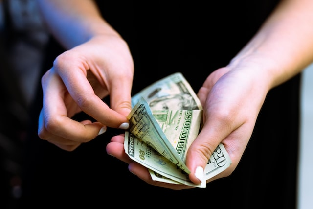 A person counting dollars saved from buying and selling products online