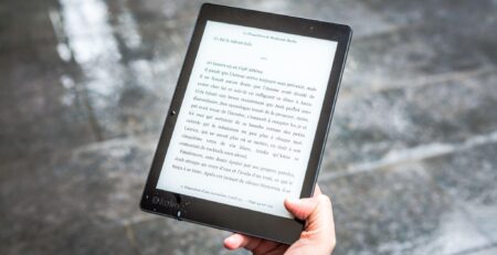 A hand holding an electronic reader open to the page of a book