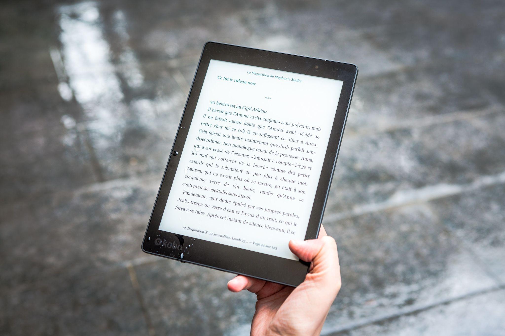 A hand holding an electronic reader open to the page of a book