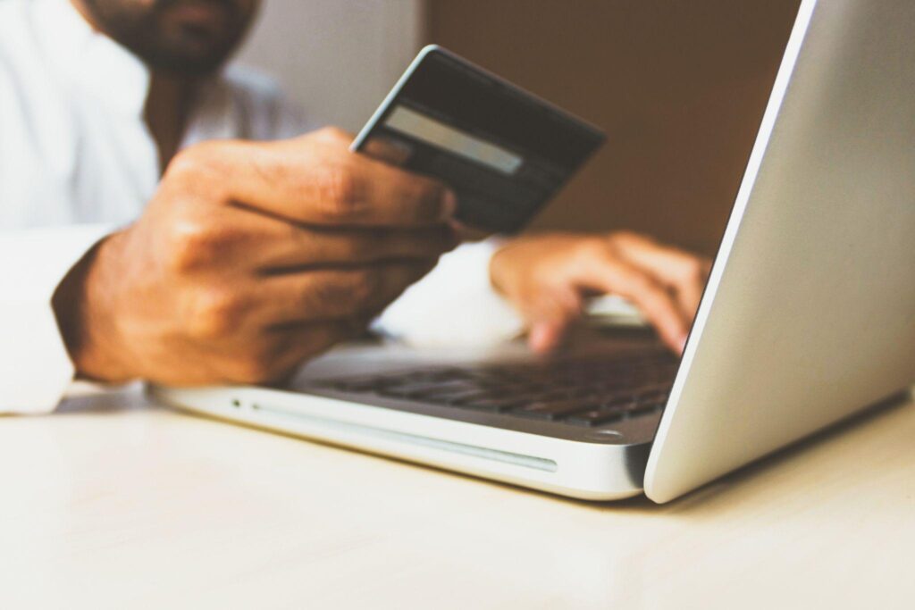 Blurred image of person checking credit card details and entering them on laptop, presumably for an online purchase