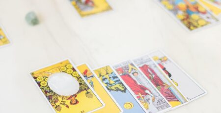 Tarot cards arranged in an organized spread on a white table with crystals lying close by.