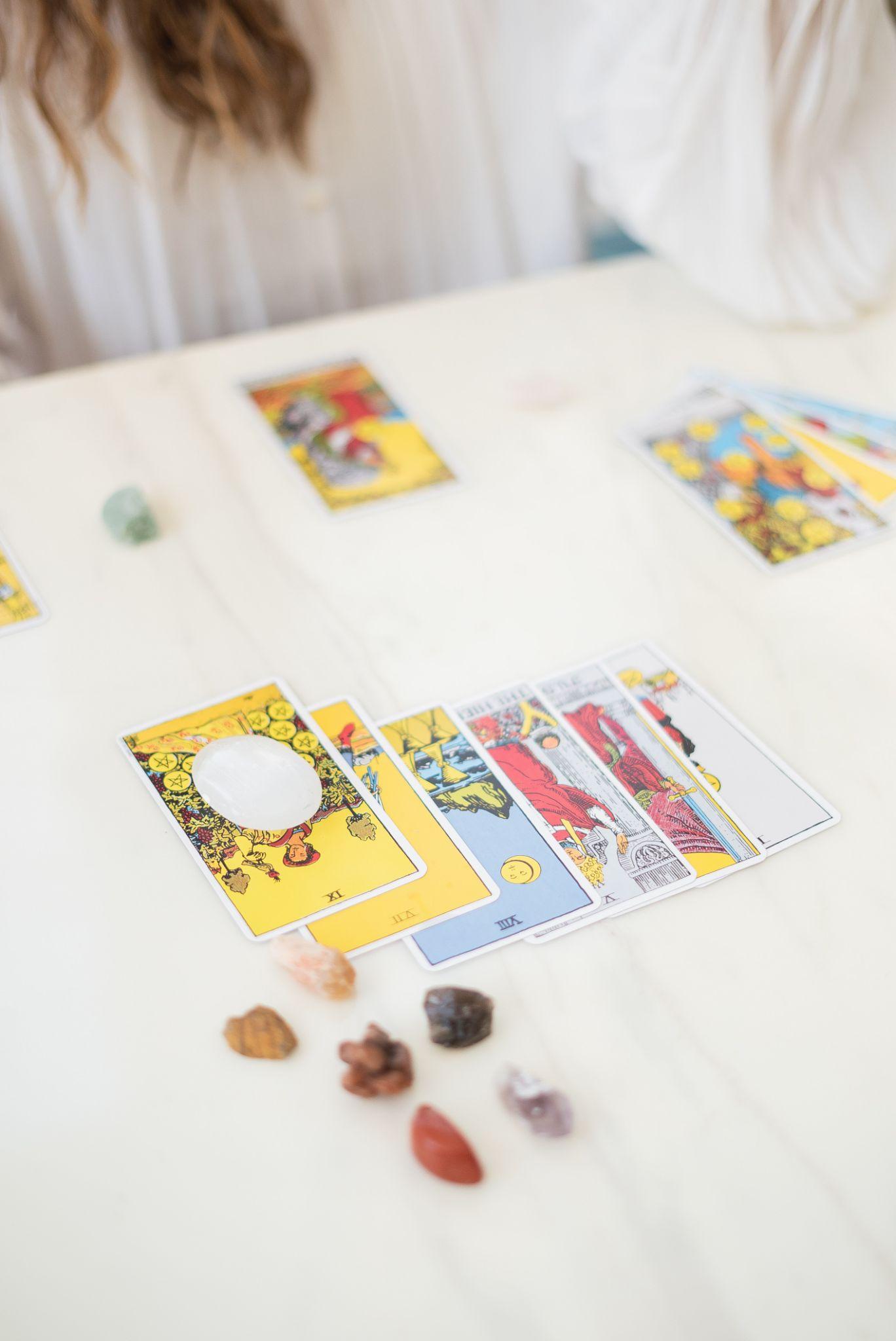 Tarot cards arranged in an organized spread on a white table with crystals lying close by.
