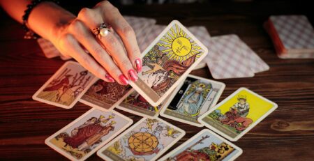 a person's hand holding up the Sun tarot card to the camera.