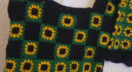 A black and green top with sunflowers on it
