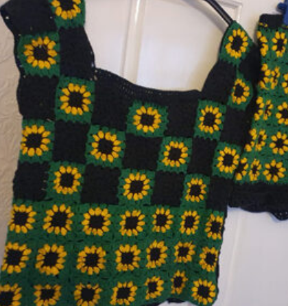 A black and green top with sunflowers on it